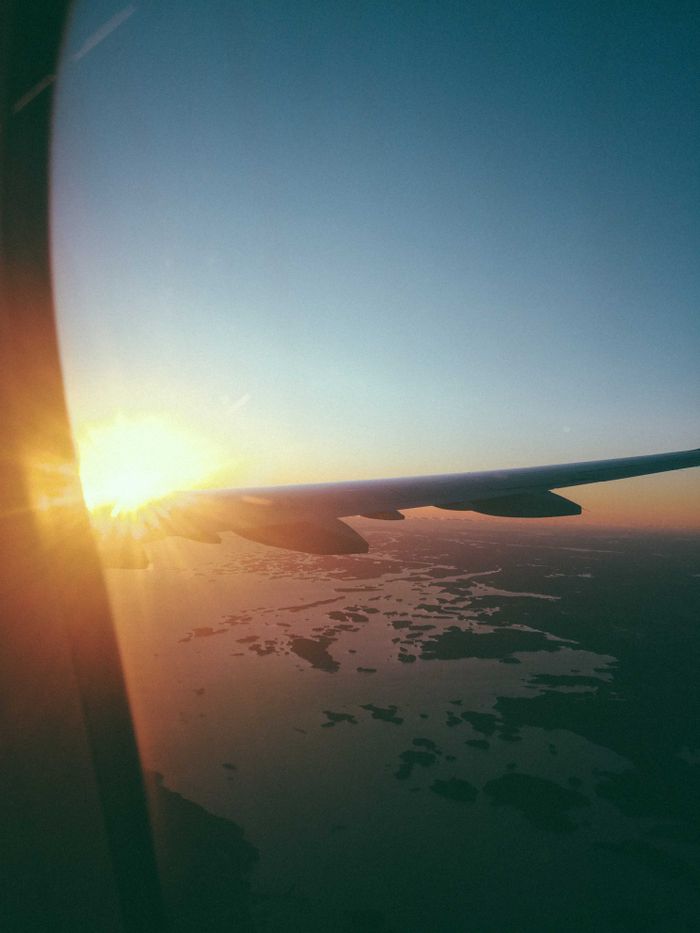 A breathtaking sunrise view captured from an airplane window, showcasing the aircraft wing and aerial scenery.